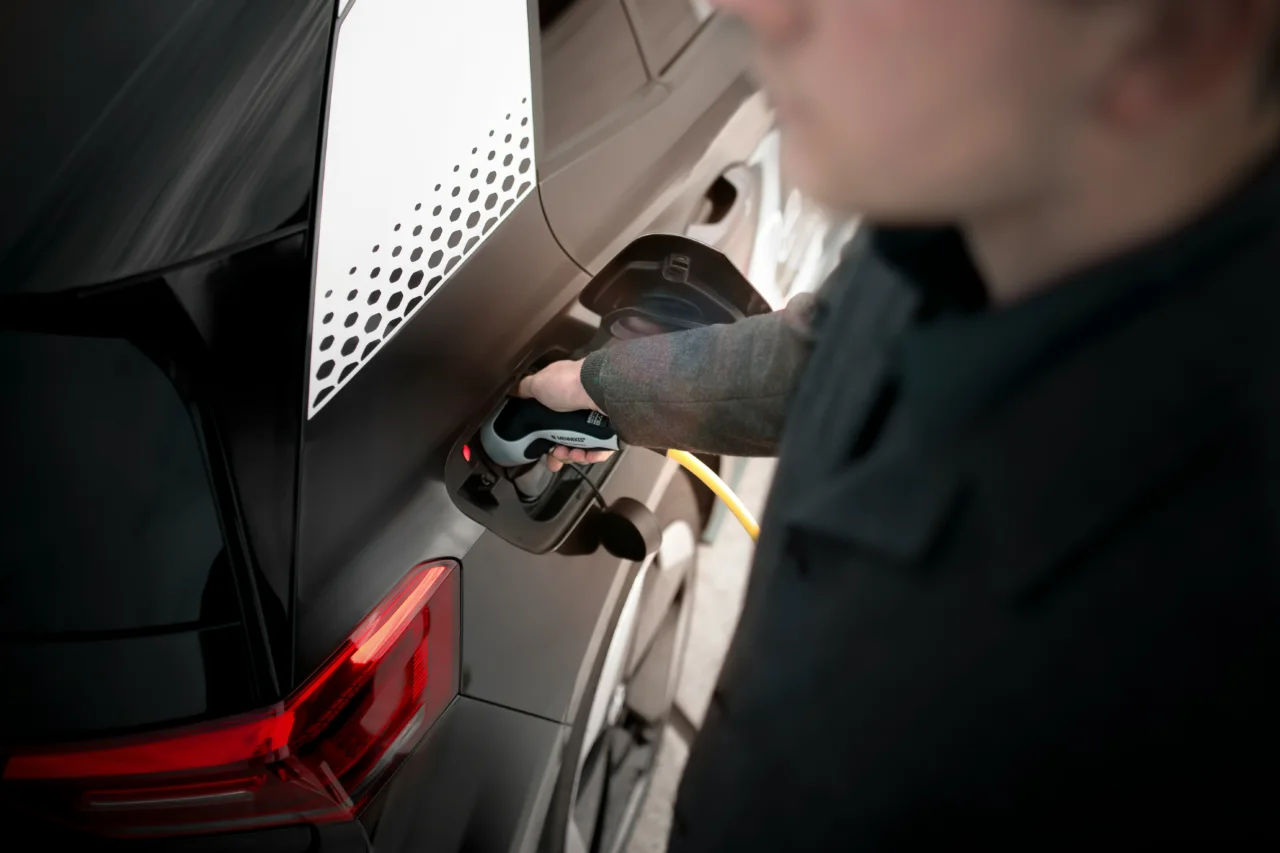 A driver connecting a charging cable to an electric vehicle